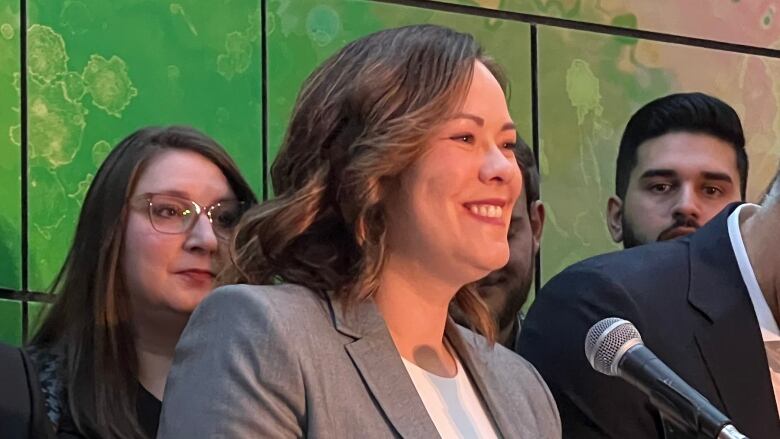 A press conference is shown with a number of people standing behind a podium.