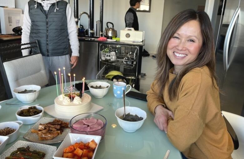 A woman sits at a table full of Korean food.