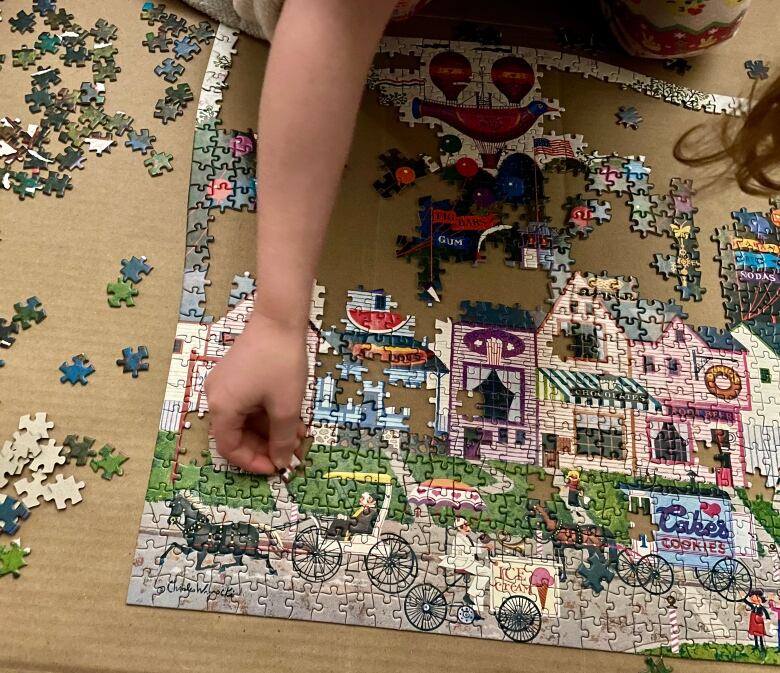 a child's hand works at solving a jigsaw puzzle