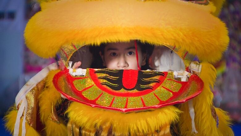 A young girl peaks through a lion dance costume