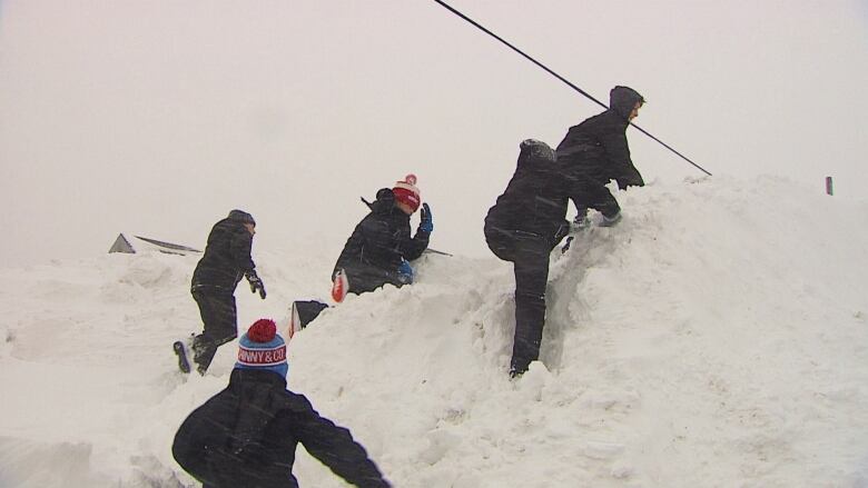 Kids climbing hill of snow.