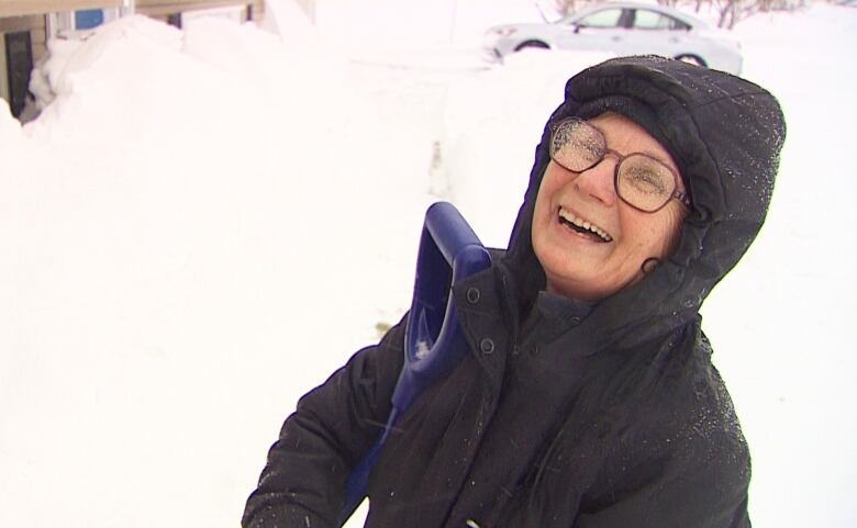 Woman in snow with shovel.