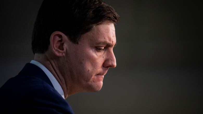 David Eby is shown in profile from the shoulders up, looking concerned.