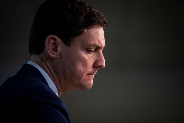 David Eby is shown in profile from the shoulders up, looking concerned.