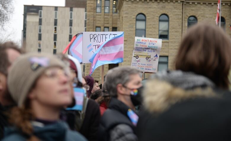 people and signs at a political rally against policies restricting transgender people's rights.