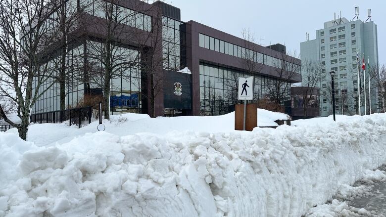 A snow bank is shown in front of a large building