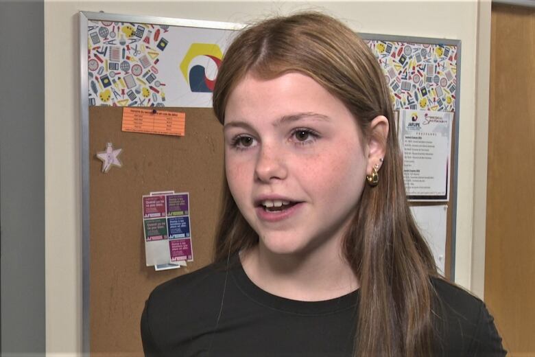 Nevaeh Dutcher in front of a bulletin board.