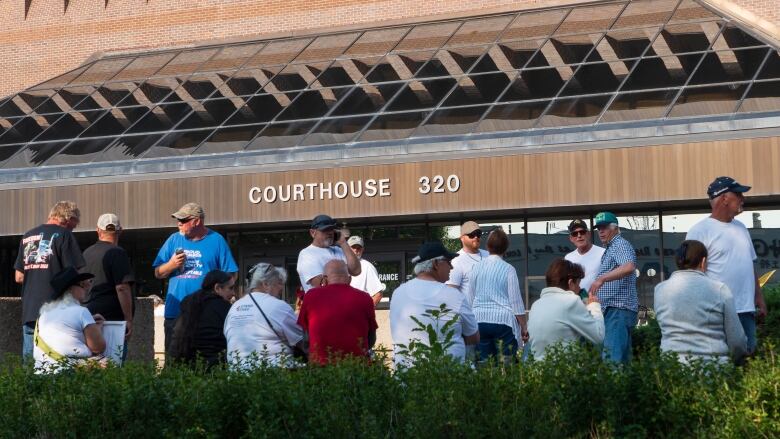 A crowd of people is shown outside a building that reads 