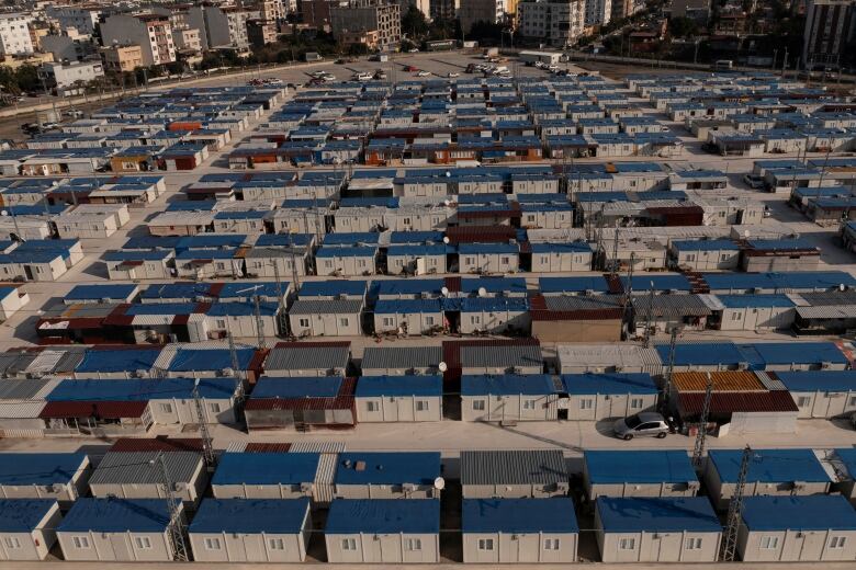 Rows of dozens of white shipping containers with windows and blue roofs.