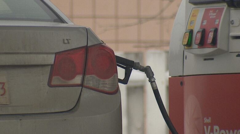 A white sedan with a gas pump in the gas cap.