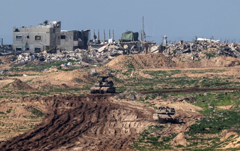 Israeli tanks are seen on the move in the Gaza Strip, with a group of destroyed buildings seen in the background.