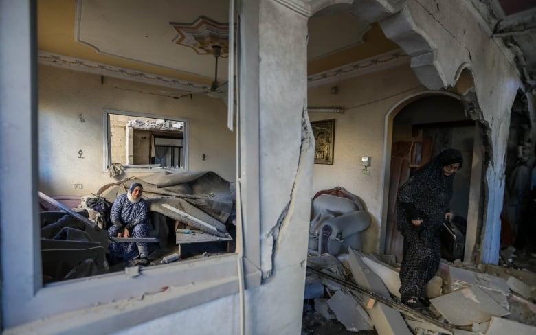 People inspect damage done by Israeli airstrikes, to their homes, in Rafah, in the Gaza Strip.