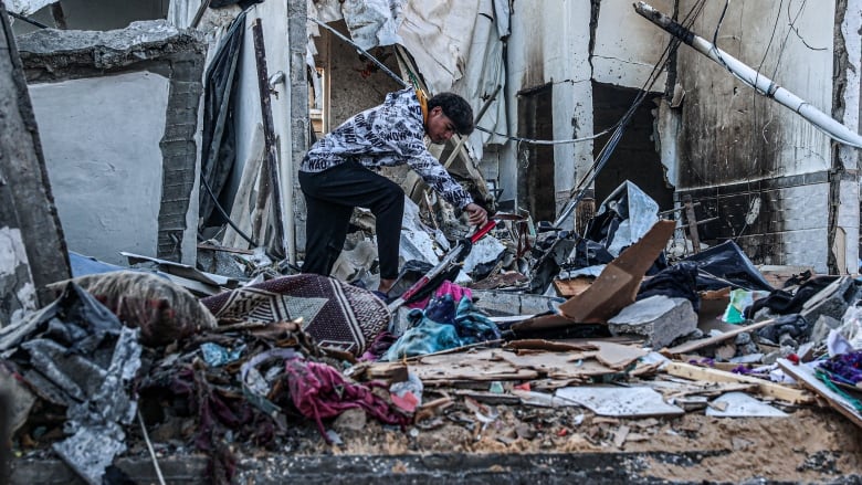 A young person looks at debris strewn about in the aftermath of Israeli bombardment in Rafah, in the Gaza Strip.