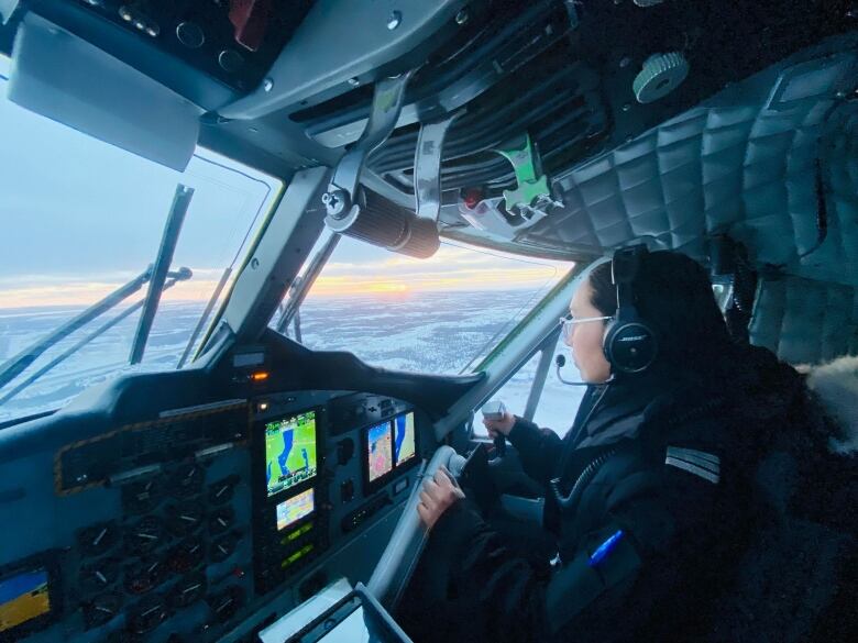 A woman in the cockpit, flying a plane. 