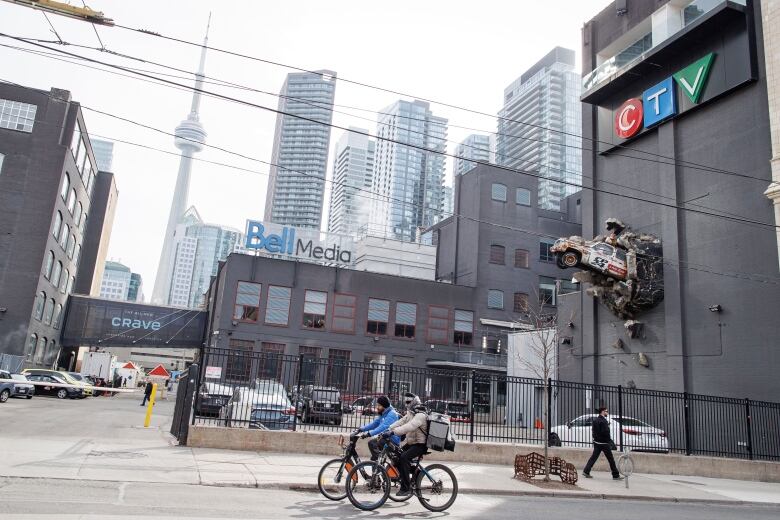 A building in downtown Toronto with Bell Media and CTV signage, and a model car with the CP24 logo on it crashing out of the side of the building.