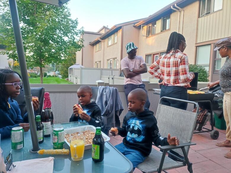 Kids and adults sit outside eating at a summer bbq.