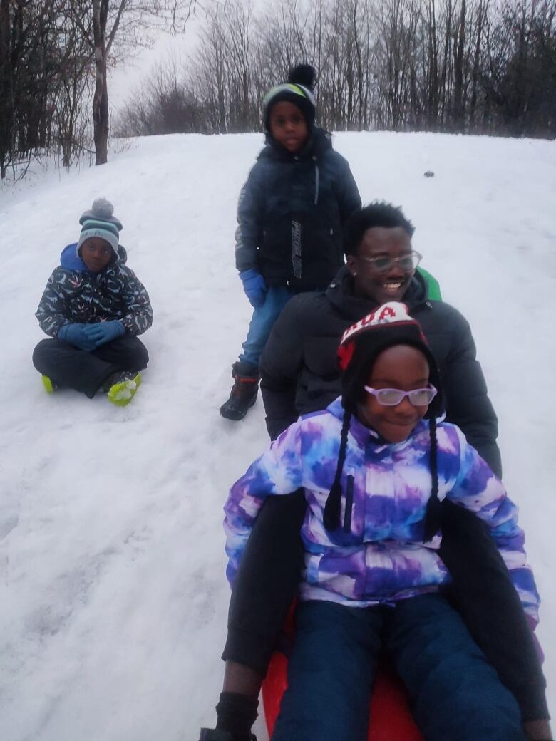 A family toboggans down a hill.