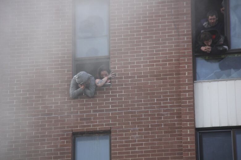 People looking out a window amid smoke