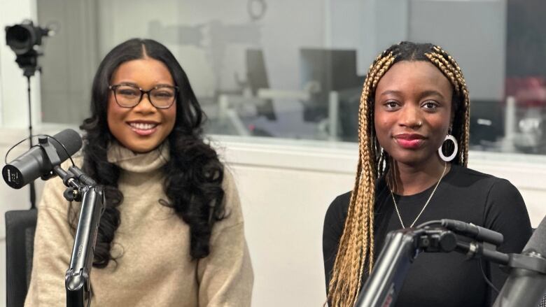 Two women sit at a table smiling.