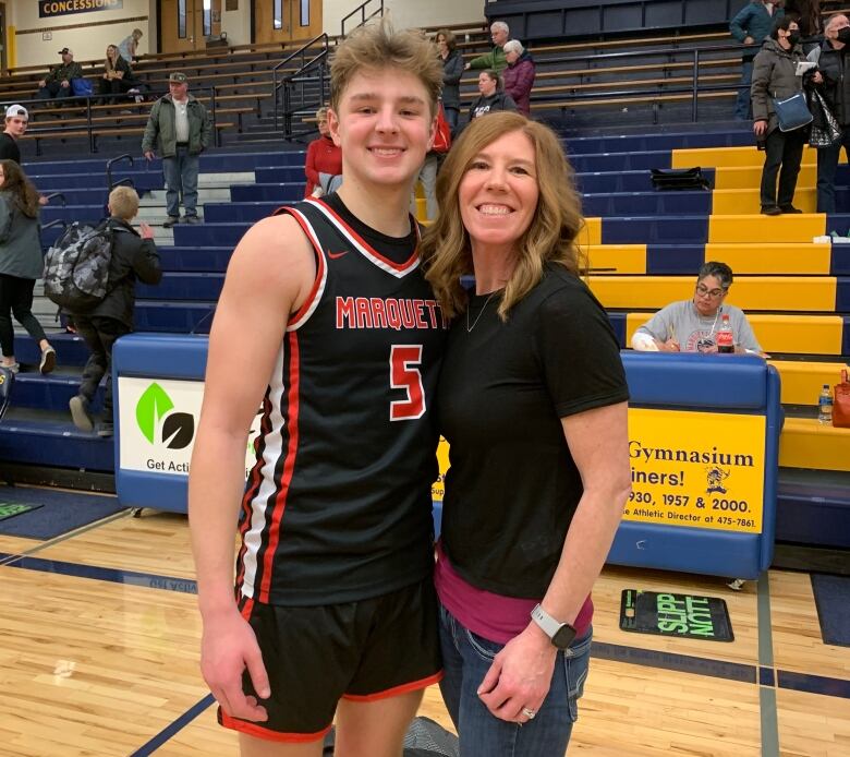 Jennifer Buta stands with her son Jordan Demay at a basketball game.