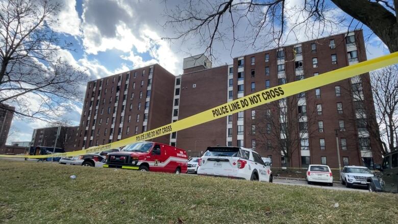 A piece of police tape, in front of a building with many broke windows. 