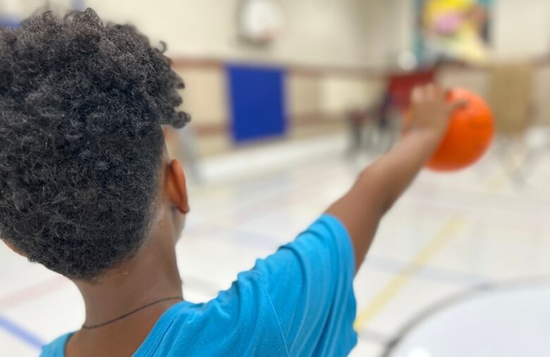 A kid holding a basketball.