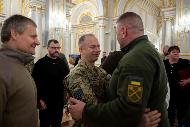 Two men in military uniforms embrace each other.