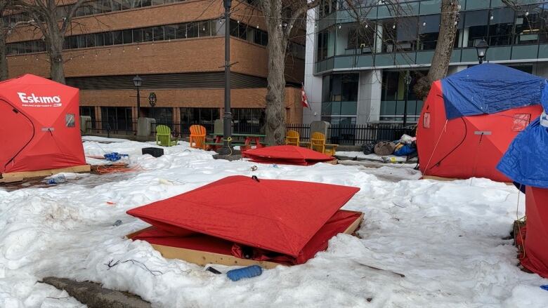 Two deconstructed red rents sit in the snow, surrounded by three other erect tents, at an encampment in downtown Halifax.