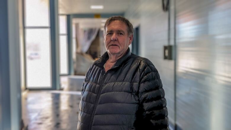 A man in a winter jacket stands in the hallway of a processing plant. 