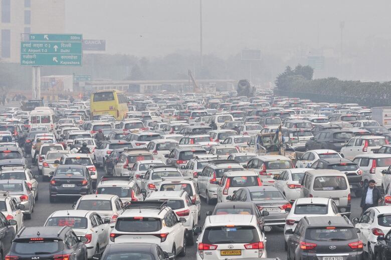 Hundreds of vehicles, mostly white, in a haphazard traffic jam in hazy conditions.