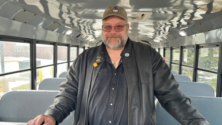 A man stands in the middle of a row of seats inside an electric school bus 