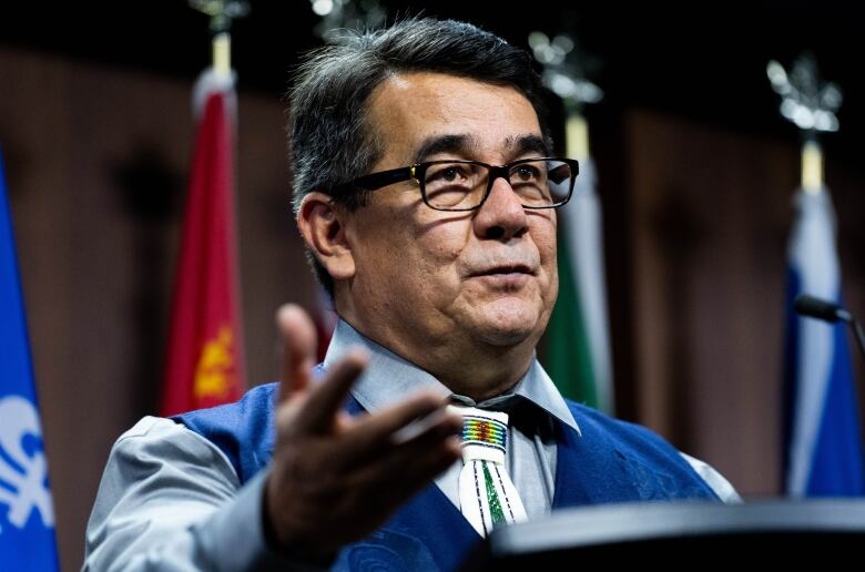 An Indigenous man gestures as he speaks at a podium.