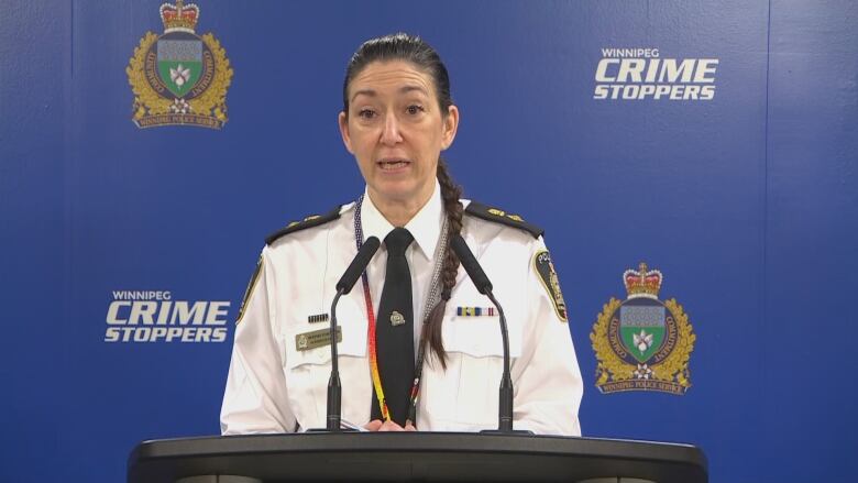 A woman in a police uniform stands behind a podium.