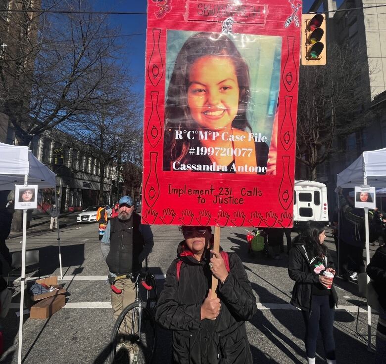 A person holds a sign with a portrait photograph and a name, Cassandra Antone, below an RCMP investigation number and the text 