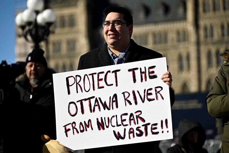 A man holds a sign on Parliament Hill.