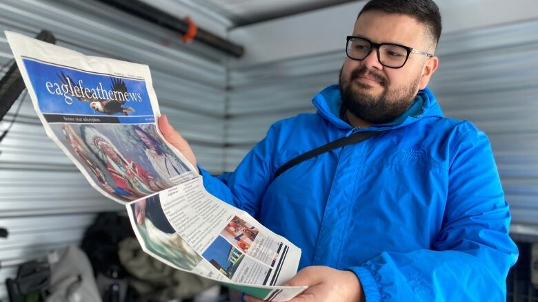 A man holds a newspaper out.