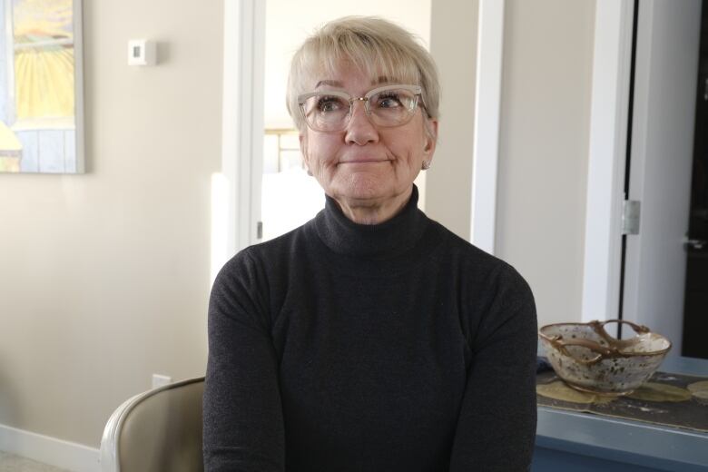 Gayle Nemeth sits in a chair in her modern looking condo kitchen