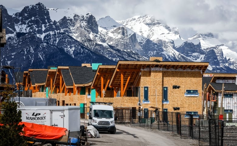 A row of new homes under construction are shown, with mountains seen in the background.