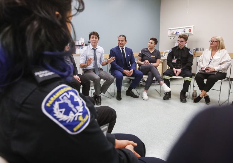 Politicians, students and health-care workers sit in a circle and talk.