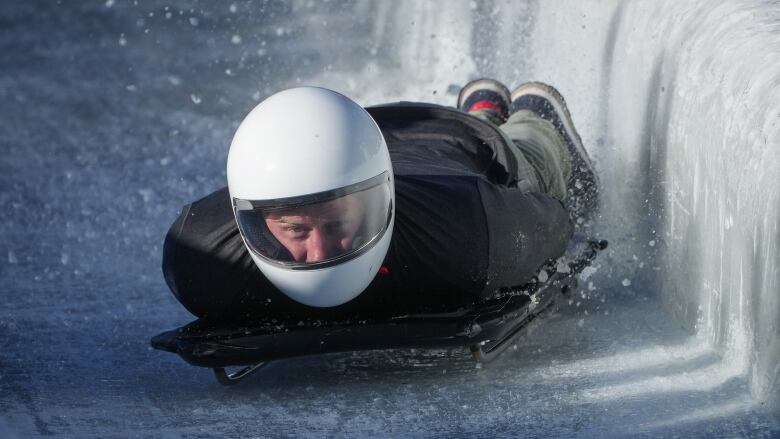 A man goes downhill in a sled face first.