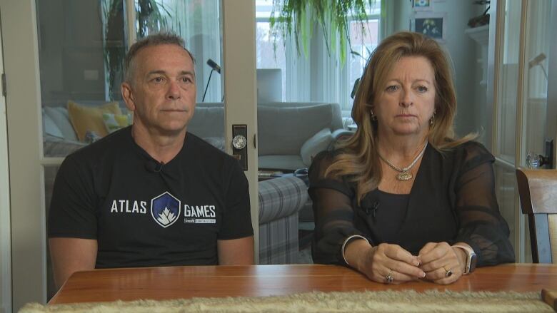 A man and a woman sit at a table in their home.