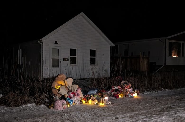 Flowers, candles and toys outside a house.