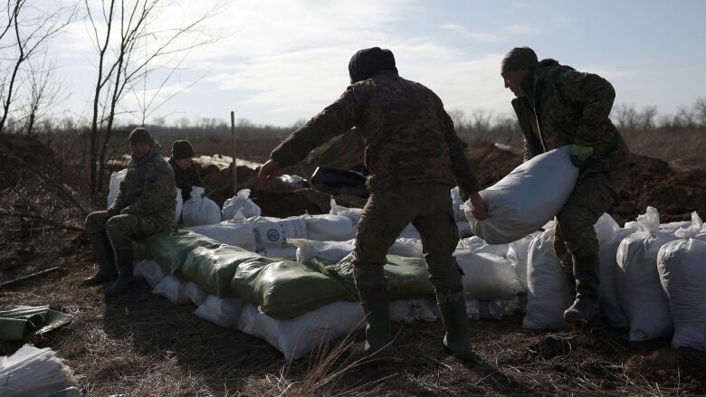 Soldiers carry sand bags at a fortified position.