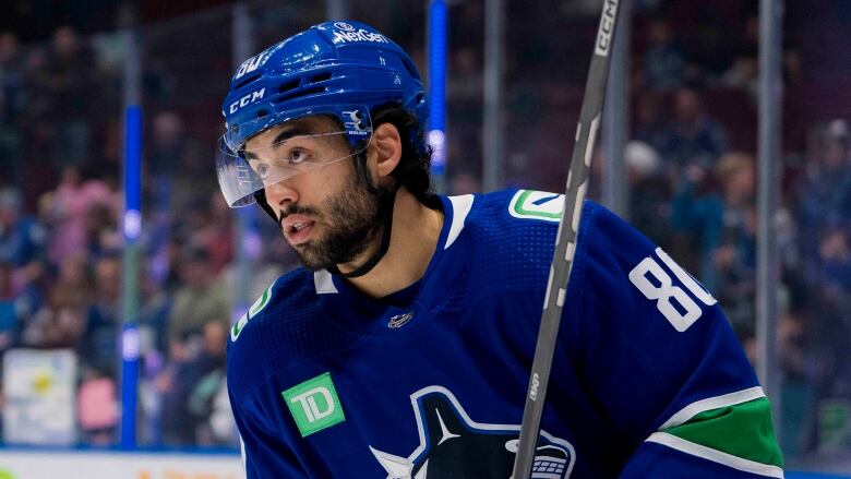 A South Asian man wearing a blue hockey uniform skates on the ice.