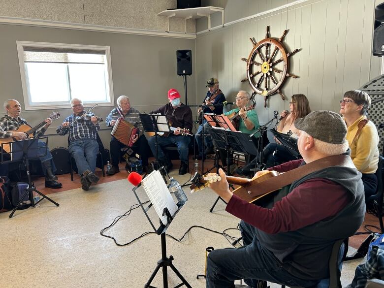 A group of musicians sits in a semi-circle. 