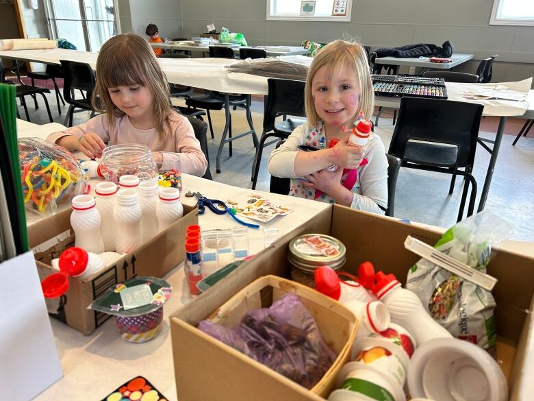 Two small girls make crafts at a table