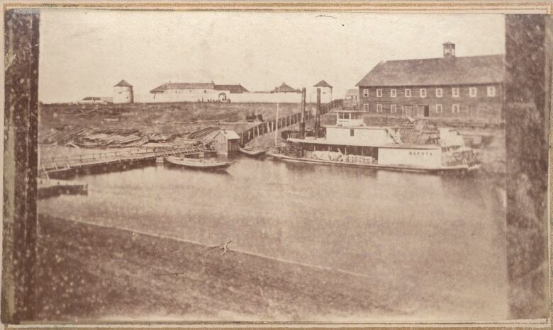 Sepia-toned photograph from 1874 shows a pontoon bridge and a boat on a river 