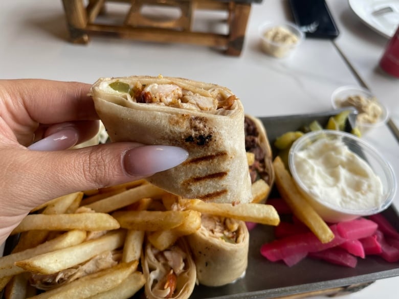 A sliced chicken wrap on a platter of fries.