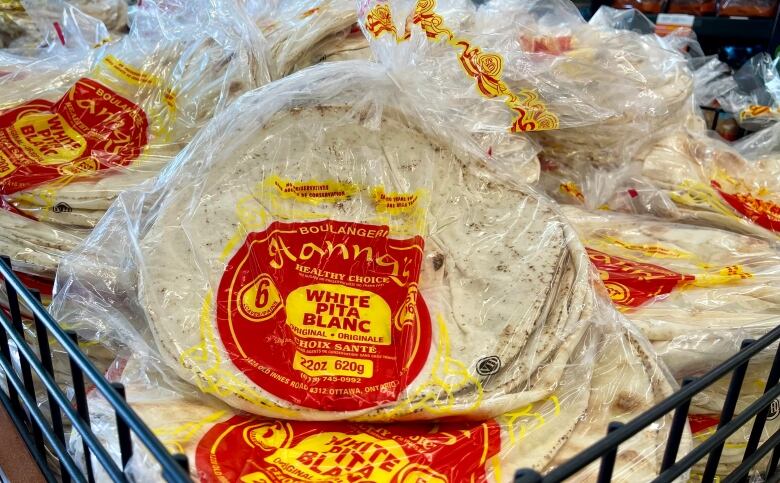 A rack of wrapped pitas with a red and yellow logo.