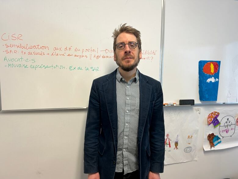 A man stands in front of a white board